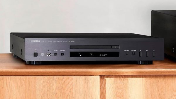 Black Yamaha CD-S303 in lifestyle setting on timber shelf next to Yamaha amplifier.